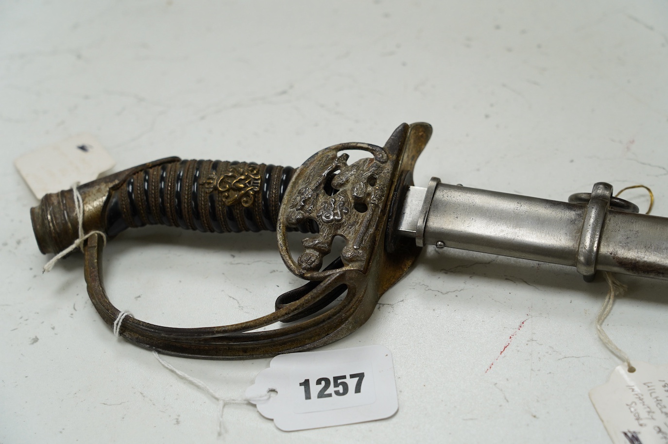 An 1889 Wilhelm II Prussian infantry officer’s sword with folding side guard, in a steel scabbard, blade 83.5cm. Condition - fair, worn overall